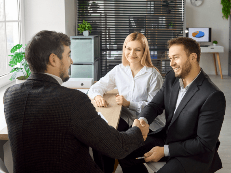 Business owners shake hands with a mortgage broker, agreeing on an emergency loan solution