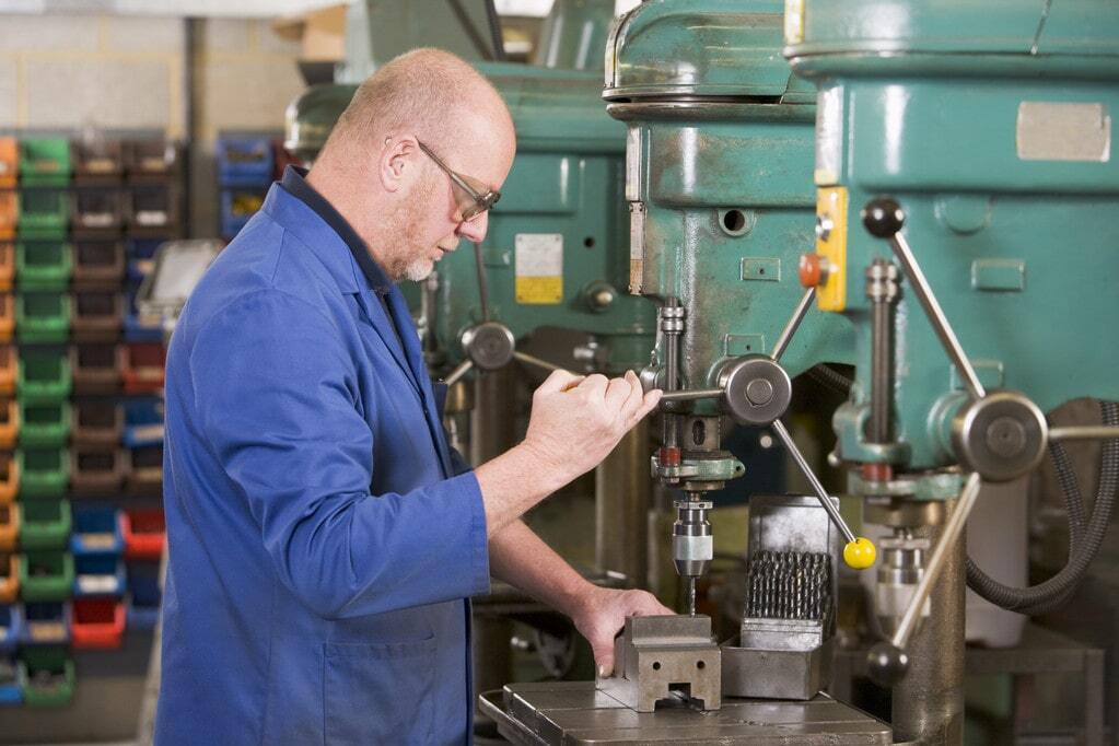 Production worker adjusting machine for a small manufacturing business
