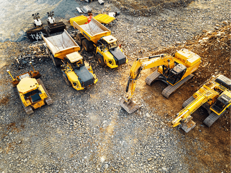 Top view of several large yellow construction equipment parked at an ongoing construction site