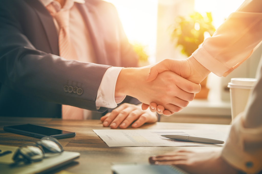 Cropped photo with atmospheric lighting, two people shaking hands with a signed document on the table between them, concept photo for getting tax debt loans approved