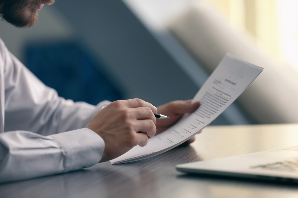 Cropped photo of businessman’s hands holding documents and a pen. Concept photo for preparing documents for a business loan.