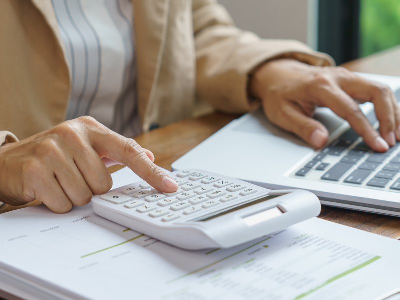 Cropped photo of a person using their laptop and a calculator, calculating cash flow and profit of a company