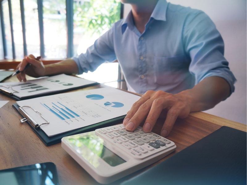 A business owner looking at documents and using a calculator, a business owner checking his budget and repayments