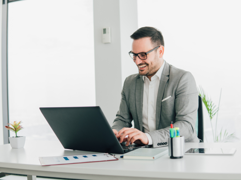 A business owner happily uses his laptop