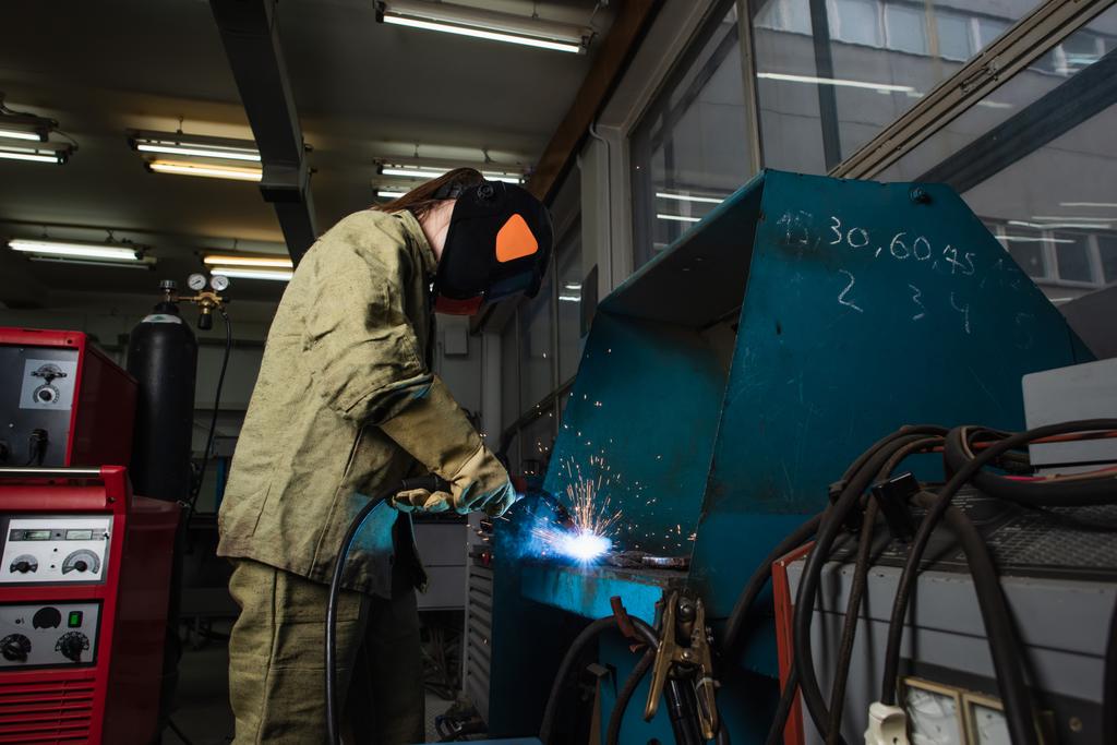 Welder in uniform and gloves working with welding torch