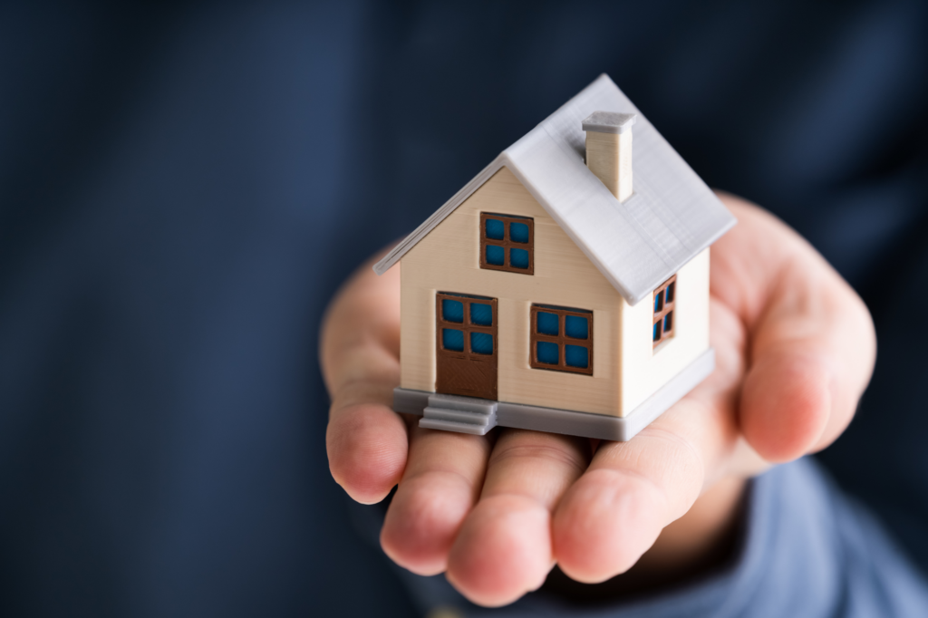 Cropped zoomed photo of a hand holding a miniature house, concept photo for using home equity for a second mortgage loan