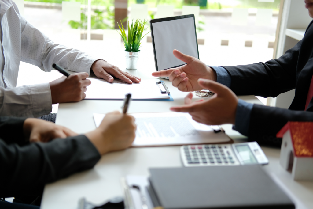 Cropped photo of two men seated across another man, discussion and signing papers, concept photo of business owners discussing a second mortgage loan with a lender or loan broker