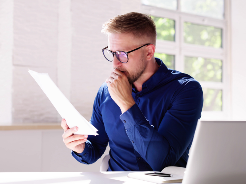 A man in glasses intently reads a document, a business owner looking at details of an unsecured loan, and deciding if it’s right for him