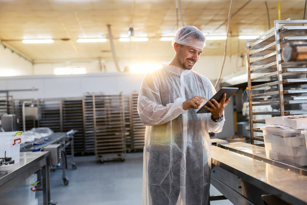 Worker looking at a tablet in an industrial food manufacturing factory.