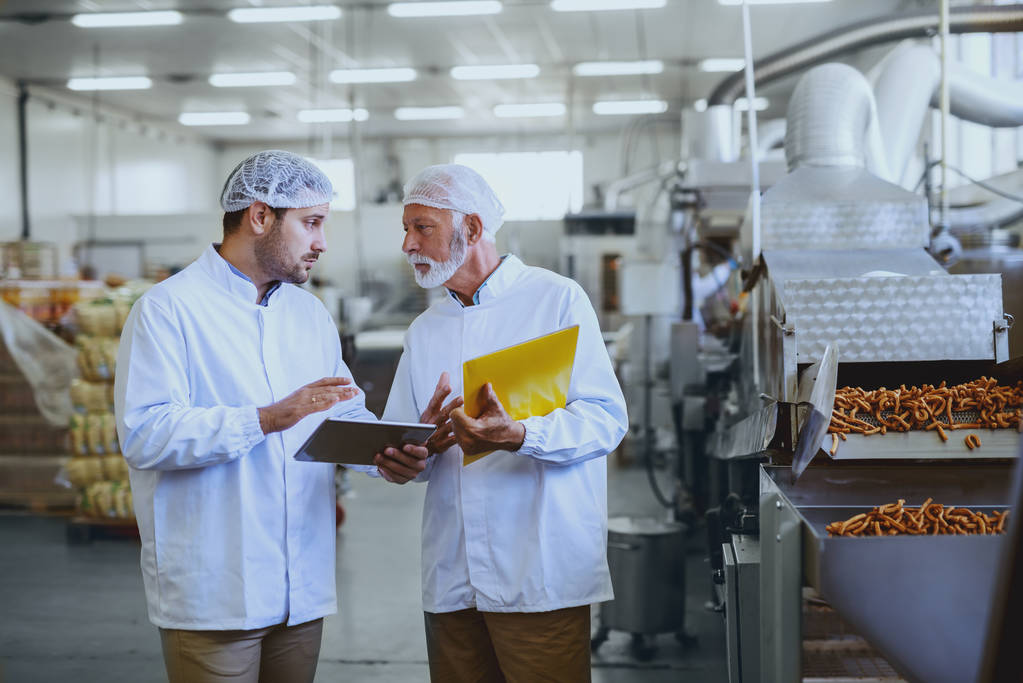Two workers discussing cash flow problems in a food manufacturing factory.