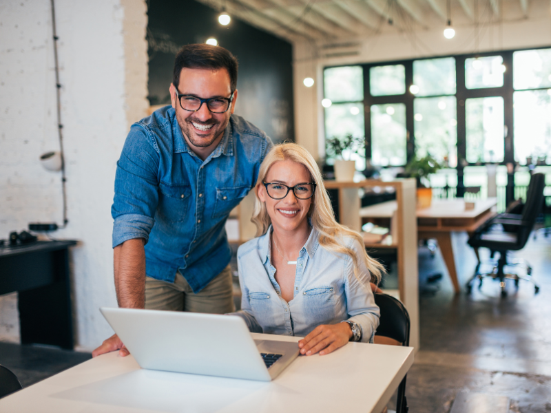 Two business owners working inside their business office, smiling at the camera