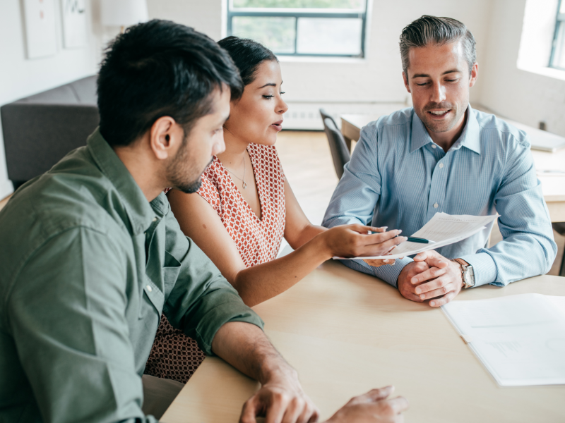 Two business owners talking to a mortgage broker about a second mortgage loan for debt consolidation
