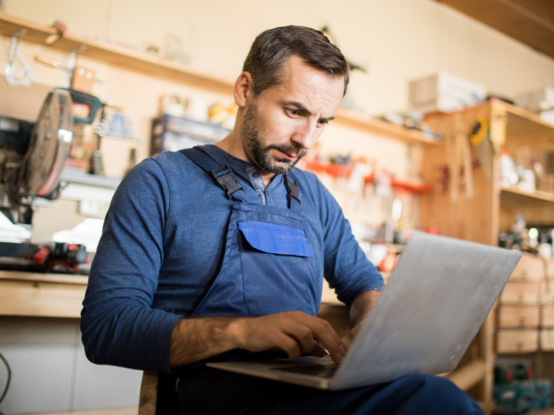 A small business owner with a stressed expression works on his laptop