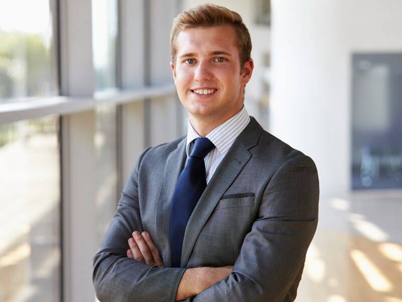 A man in a suit poses for the camera, smiling with his arms crossed, business owner happy to have found a business line of credit solution