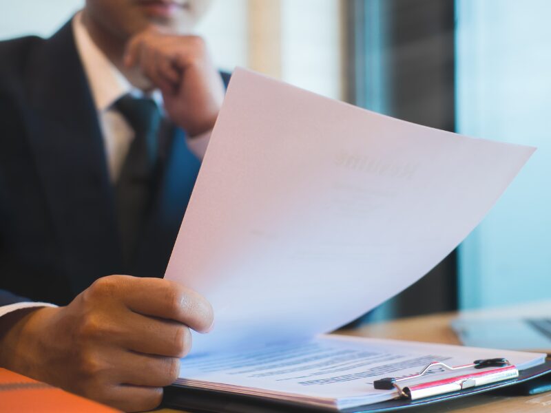 Cropped photo of a man in a suit reading documents intently with his hand on his chin