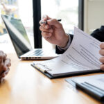 loan expert explaining how a loan works, hands only, man holding document and pen, client on left hands together