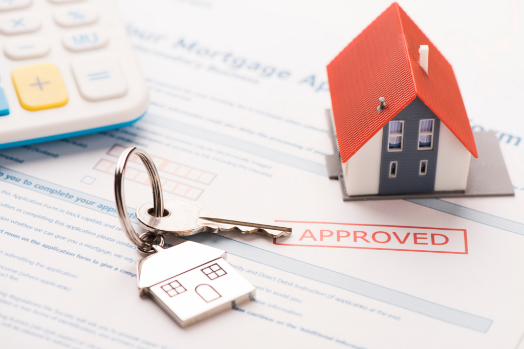 Key, house figurine, and calculator on top of an approved mortgage application form
