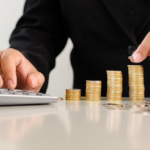 Cropped image of businessman in a suit piling gold coins, conceptual photo for raising business capital