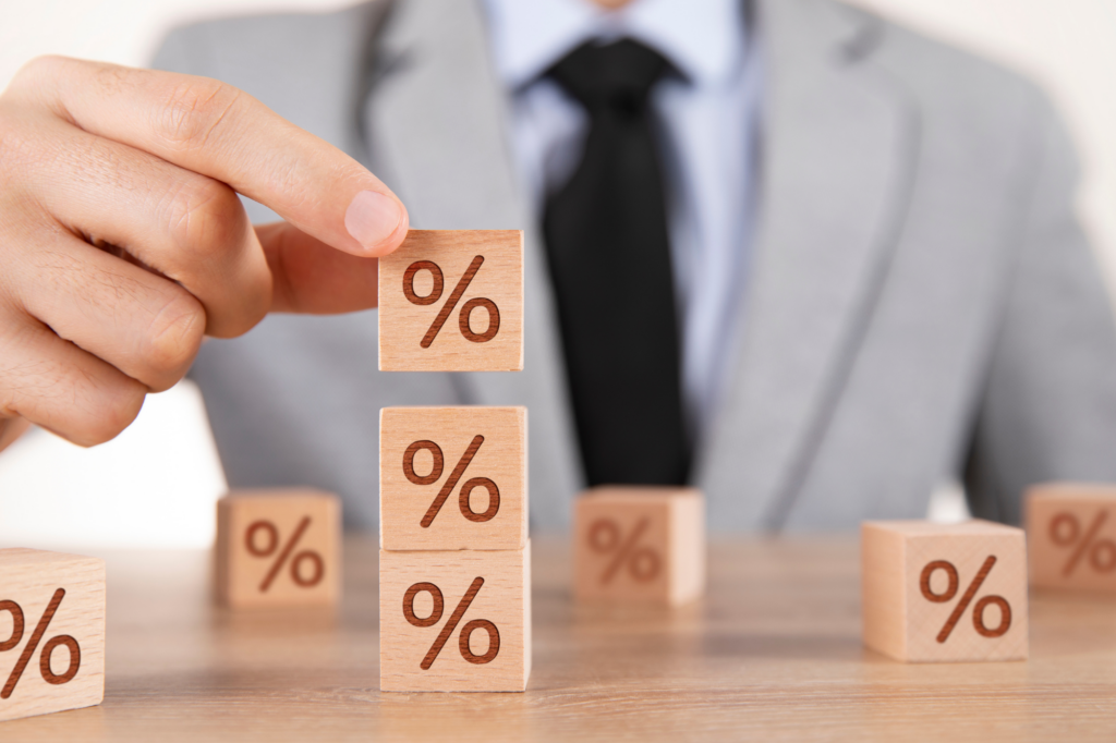 Cropped photo of man in business attire stacking wooden boxes with the percentage sign, concept photo of comparing home loan interest rates