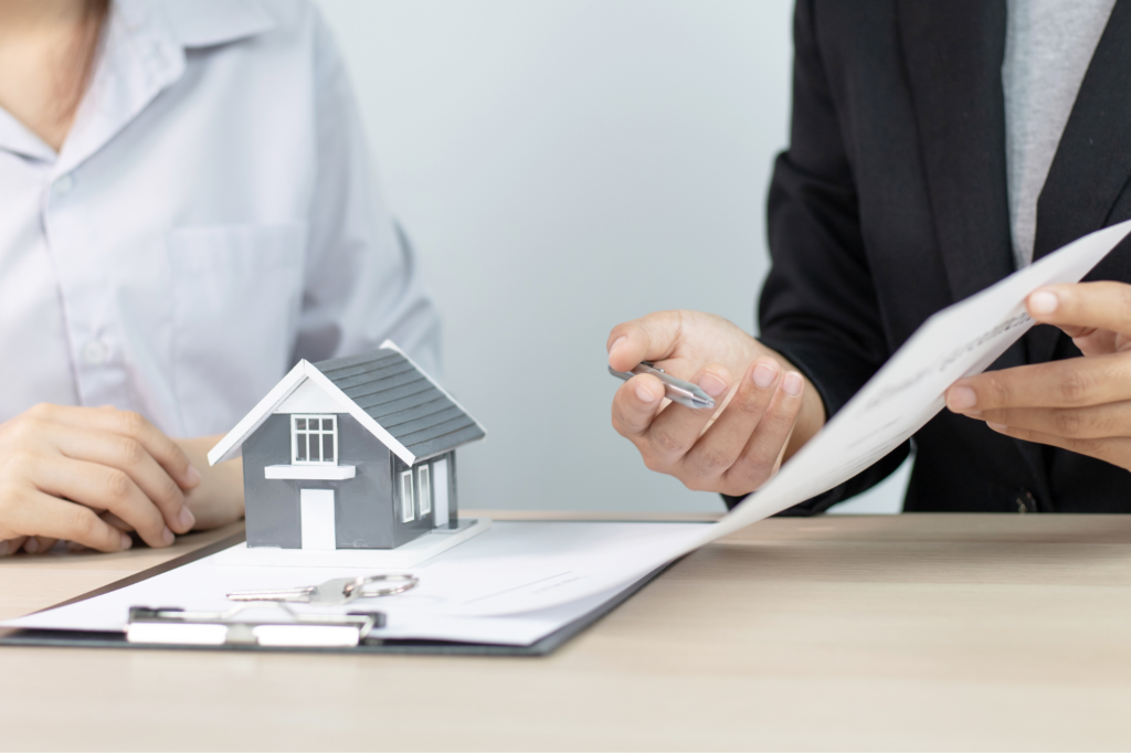 Cropped photo of mortgage broker explaining refinancing options to his client, clipboard with documents, miniature model house, concept photo