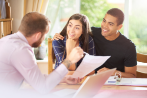 couple happily discusses mortgage refinance with mortgage broker, brightly lit photo, happy mood
