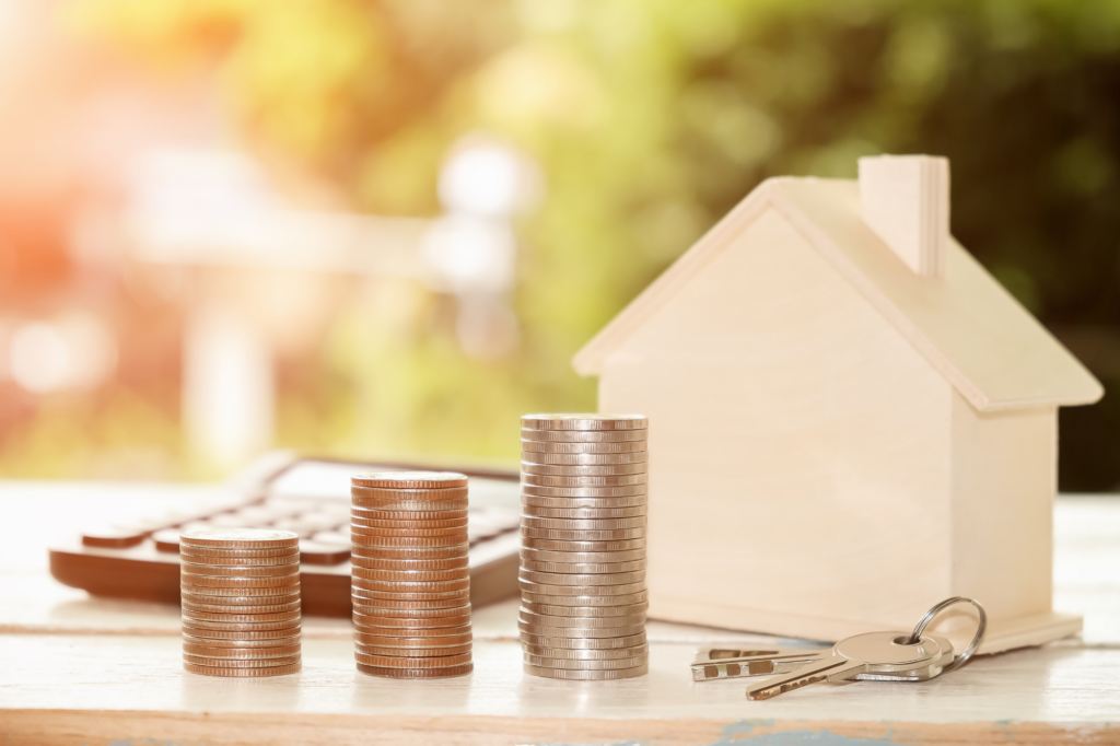 Coins stacked next to miniature wooden model house, concept photo for SMSF loans