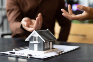 Client and mortgage broker or lender discussing SMSF loans for investment, concept photo, cropped photo of discussion, files and model miniature house visible