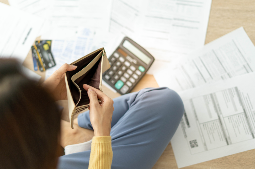 Top view of a woman surrounded by documents and calculator, holding an empty wallet, business owner going into insolvency and bankruptcy