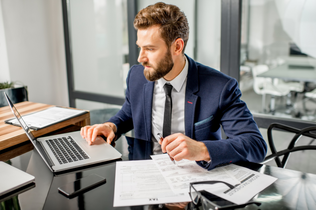 Sharply dressed adult man, businessman intently staring at his laptop screen, business in tax debt