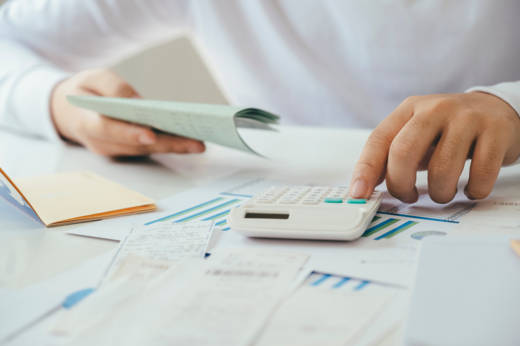 Cropped photo of man using calculator and holding documents, calculating taxes and other business expenses