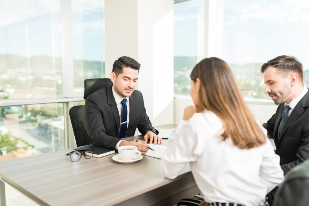 Business owners apply for a business loan in Australia, couple sitting together with loan broker or lender on the opposite side of the table, showing loan details, showing documents