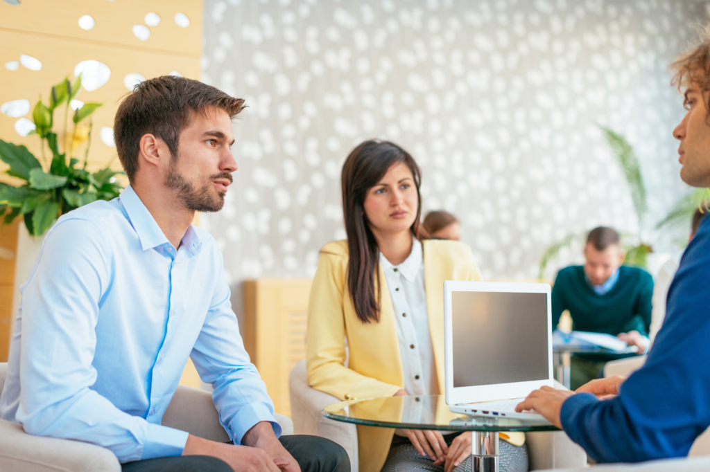 Couple sitting across a professional, concentrated and focused expressions, concept photo for business owners weighing the pros and cons of a caveat loan with a lender or loan broker