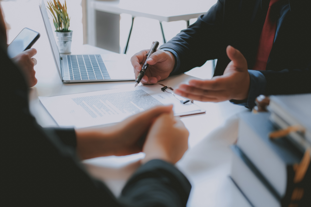 Cropped photo of two professionals discussing documents, hands, pen, and clipboard with documents visible, concept photo for discussing debts and debt consolidation solutions