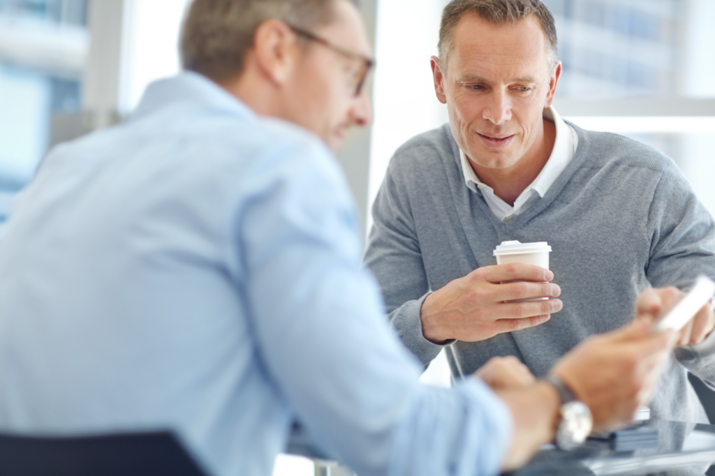 Two men sitting across from each other examine a document together, concept photo for a business owner applying for private lending in Australia