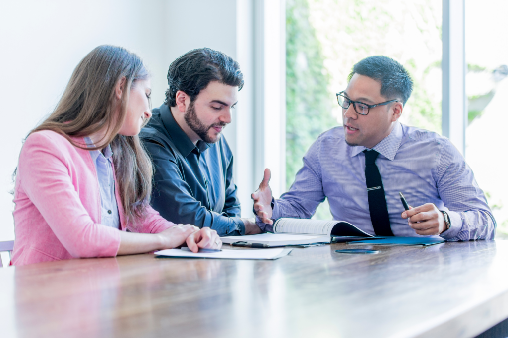 A business-owning couple reads documents as a lender or broker explains details, concept photo for business owners getting private lending in Australia