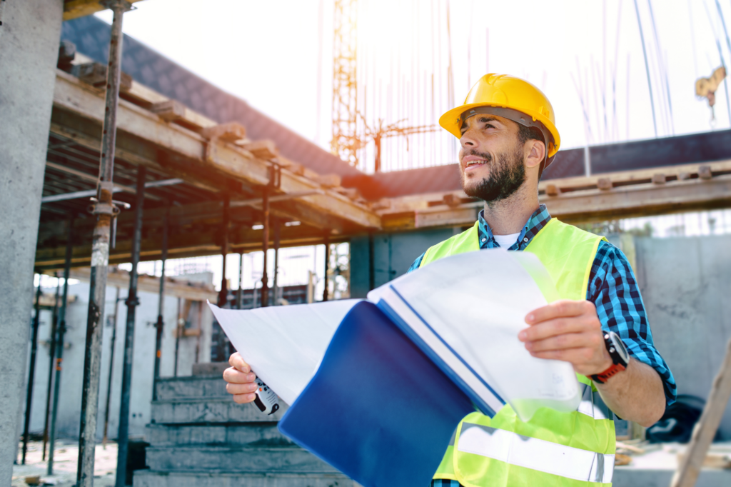 Construction engineer or business owner holds building plans and looks optimistic, looking at the distance