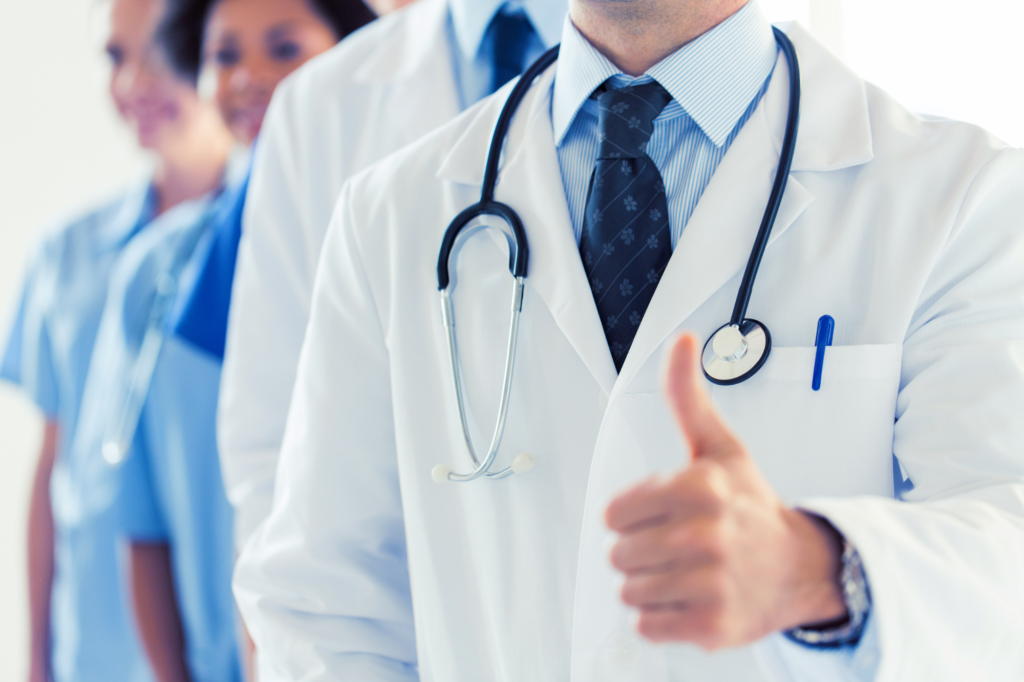 Cropped photo of medical professionals, with the doctor in front showing a thumbs-up gesture, concept photo for a doctor getting funding for their medical practice