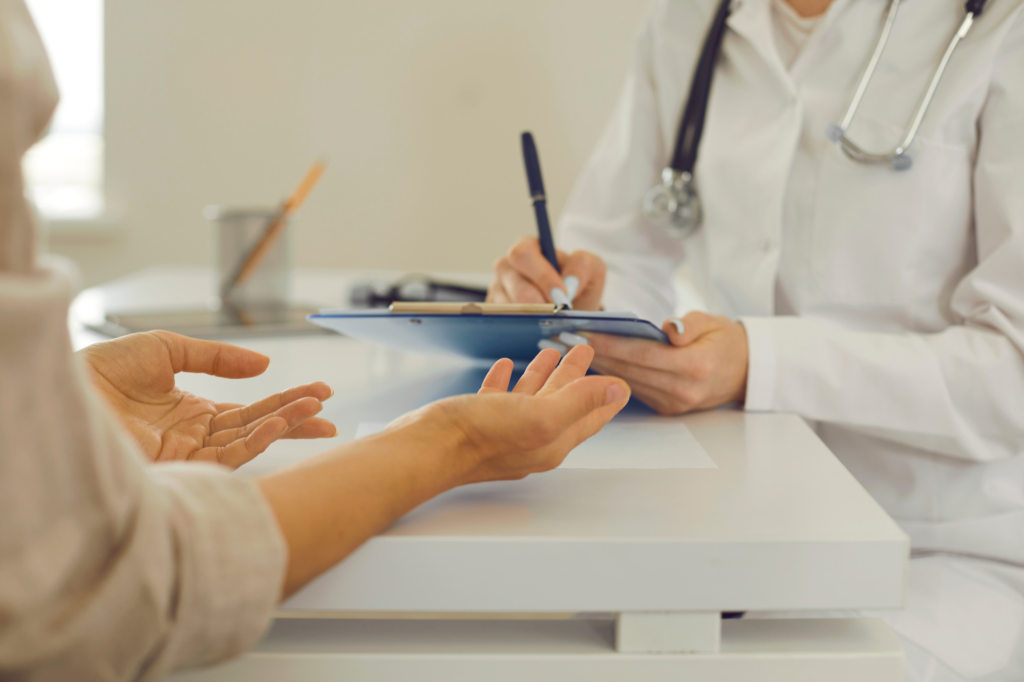 Cropped photo of a doctor and patients’ hands, discussing results, doctor writing on a document on a clipboard, clinic appointment, doctor setting up own practice after getting medical practice loans