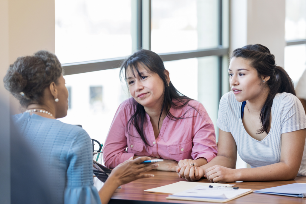 An older woman and a young woman sit across the table from another woman, having a discussion, concept photo for getting a cash flow loan from a lender or loan expert