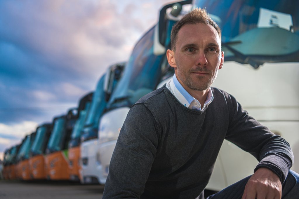 man sitting and smiling in front of truck fleet