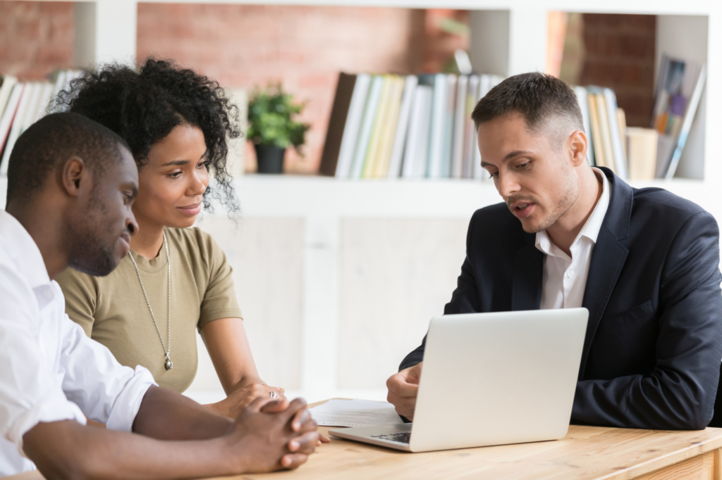 A couple sits across a man in a suit looking at the display on a laptop, concept photo for business owners considering a private lender