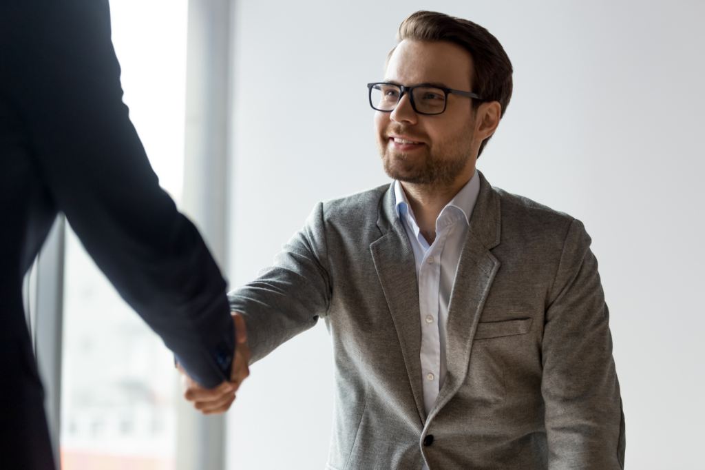 A man in glasses shakes the hand of another man off-photo, photo of business owner finding a good private lender for a business loan