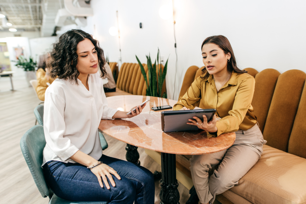 Two women having a one-on-one meeting, one woman discussing what’s displayed on her tablet, other woman paying attention, concept photo for a private lender meeting with a business owner