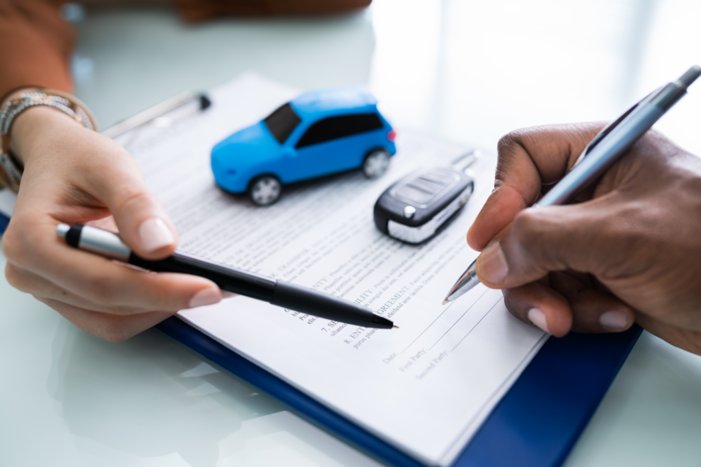 Cropped photo of two hands holding pens, one pointing at a section in a document and one signing, toy model car and car key visible, concept photo for signing a car loan