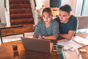 A couple intently reads the display of a laptop, business owners reviewing their tax debt and applying for an ATO payment plan