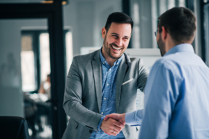 Two men in a professional setting cheerfully shake hands, concept photo of a business owner agreeing to a no doc or low doc business loan