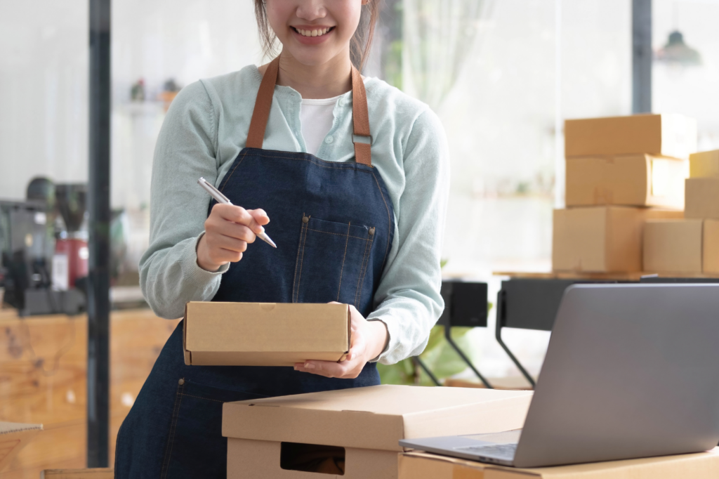 Cropped photo of a young woman in a denim and leather apron, sorting boxes for her small business, concept photo for small business owner sustaining operations with a cash flow loan