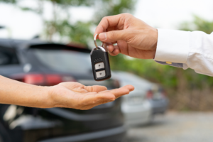 Cropped photo showing just the hands of two people, a man gives another man the keys to a new car, concept photo for a car loan being approved