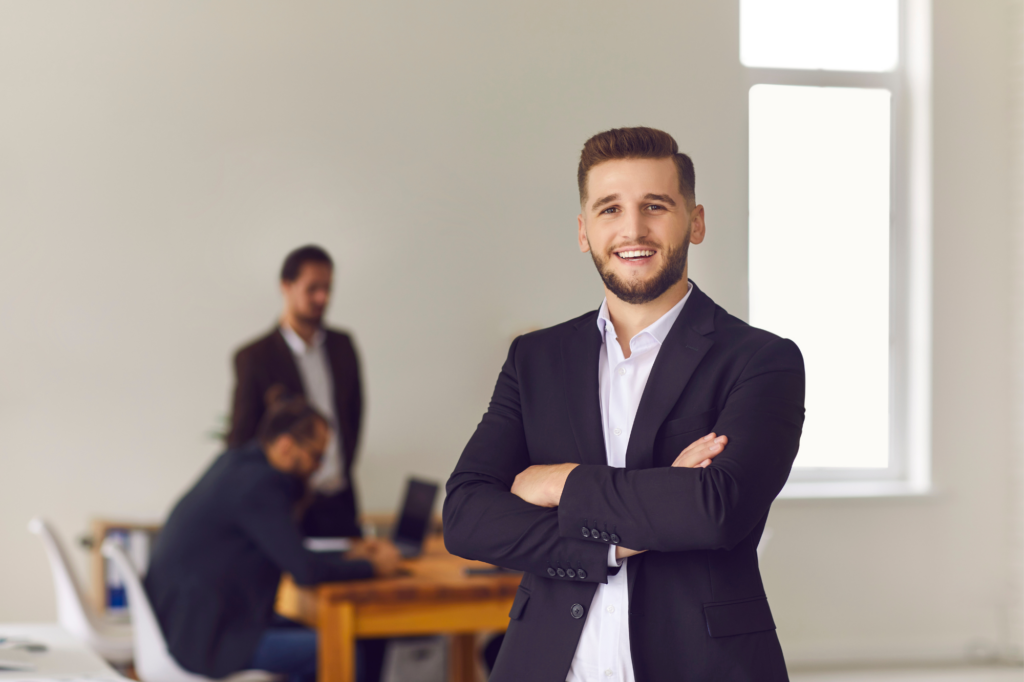 A man in a suit confidently crosses his arms and smiles directly into camera, a relaxed and confident businessman after clearing his debt with the ATO using a tax debt loan