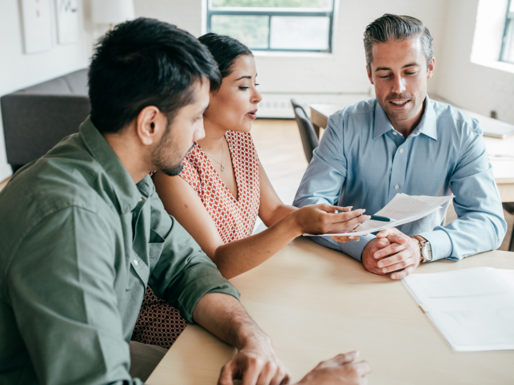 A man and a woman intently discuss the contents of a document, borrowers discussing second mortgage loan terms with a lender or broker